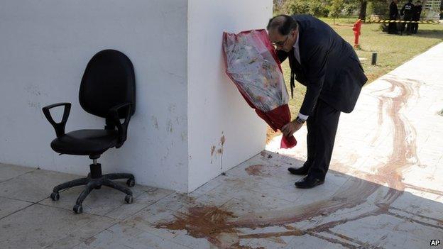 Souheil Alouini, a member of Tunisian parliament lays flowers next to a a blood stain at the Bardo museum in Tunis, Thursday, March 19, 2015