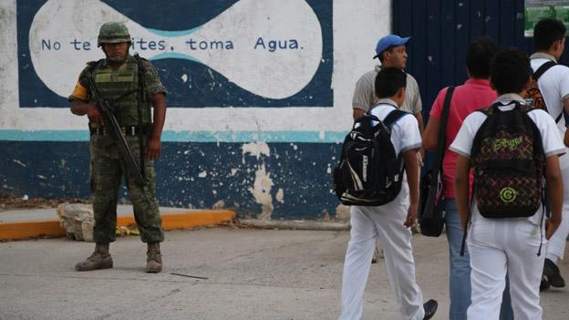 A soldier watches as children arrive for school in March 2015