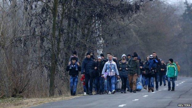 Kosovan migrants walk on a road after illegally crossing the Hungarian-Serbian border near the village of Asotthalom February 5 2015