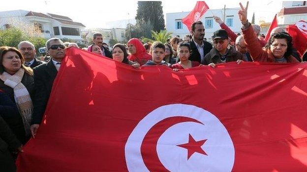 Tunisians wave their national flag as they protest outside the National Bardo Museum in Tunis, Tunisia on 19 March 2015