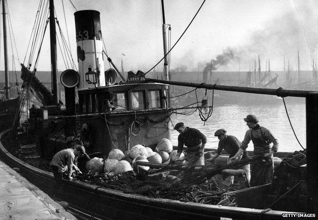 Circa 1950: Fishermen preparing their nets on board a trawler at Lowestoft.