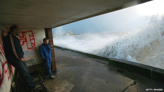 People watch as wave crash into the sea wall at Lowestoft