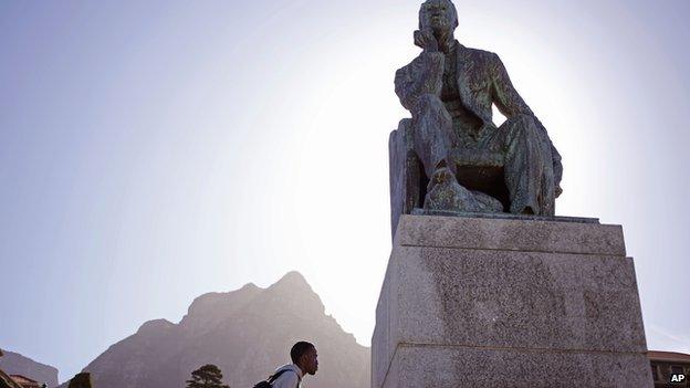 A student walks pass a statue of Cecil John Rhodes, University of Cape Town