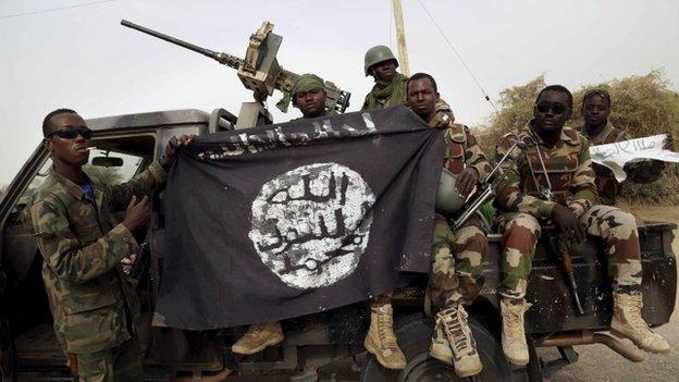 Nigerien soldiers hold up a Boko Haram flag that they had seized in the recently retaken town of Damasak