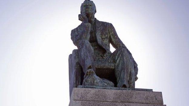 A student walks pass a statue of Cecil John Rhodes, University of Cape Town