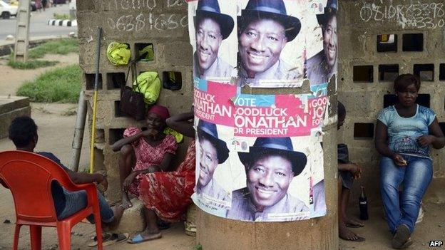 Workers sit beside campaign posters of Nigerian President and presidential candidate of ruling People's Democratic Party (PDP) Goodluck Jonathan in Lagos, on 4 March 2015