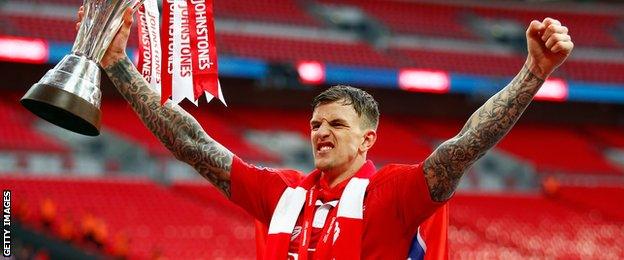 Aden Flint holds the Johnstone's Paint Trophy following Bristol City's win