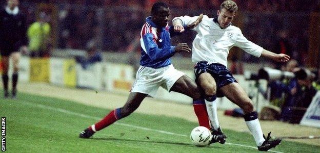 Alan Shearer is challenged by France's Basile Boli on his England debut