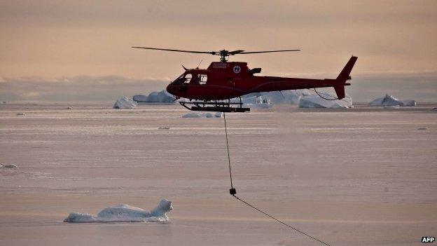 A helicopter pulling fuel lines ashore from the Australian icebreaker Aurora Australis during refueling operations at Australias Davis station in Antarctica.