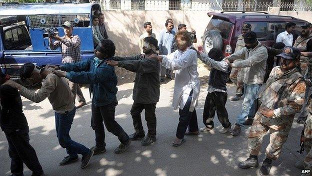 Pakistani paramilitary officials escort blindfolded activists of Muttahida Qaumi Movement (MQM) political party to a court in Karachi on March 12, 2015