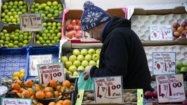 A stall worker bags up fruit for a customer at a market in Soho, central London