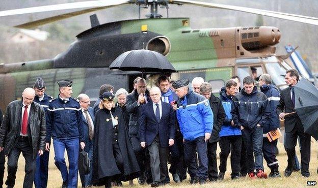 French Interior Minister Bernard Cazeneuve is sheltered from the rain upon his arrival in Seyne, south-eastern France, 24 March 2015