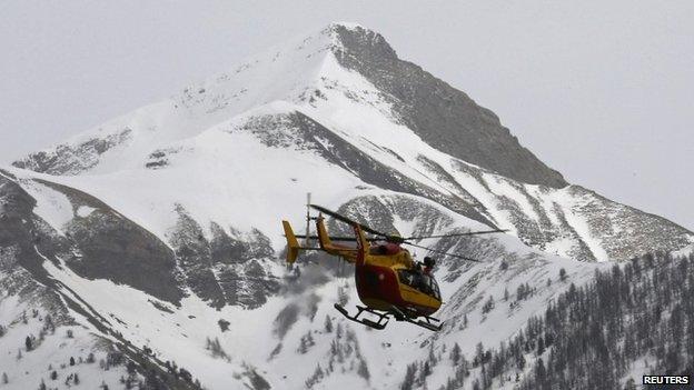 A rescue helicopter from the French Securite Civile flies over the French Alps during a rescue operation next to the crash site of an Airbus A320