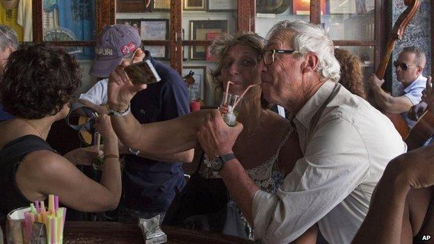 Tourists pose for a photo while sipping on a cocktail at the Bodeguita del Medio Bar in Havana on 22 March, 2015.