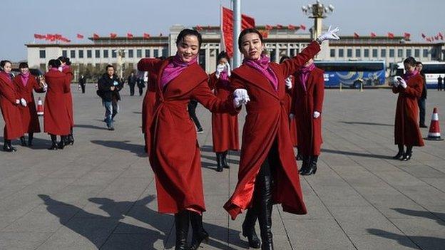 Two Chinese hostesses dance during the third session of the 12th National People's Congress outside the Great Hall of the People in Beijing on 8 March 2015