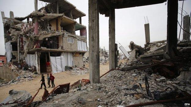 Palestinians walk past destroyed buildings in Gaza City's Shejaiya district (23 February 2015)