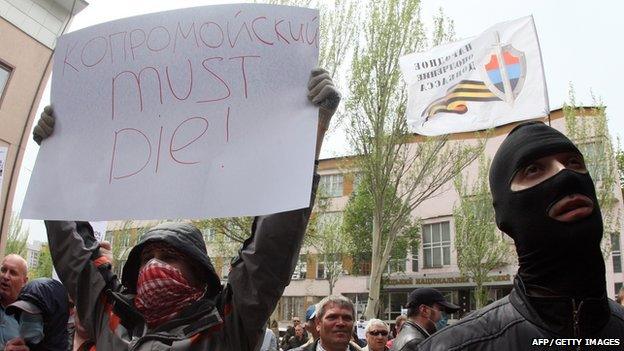 A pro-Russian militant holds a placard reading 'Kolomoisky must die!' during an attack on Privatbank in the eastern Ukrainian city of Donetsk, 28 April 2014