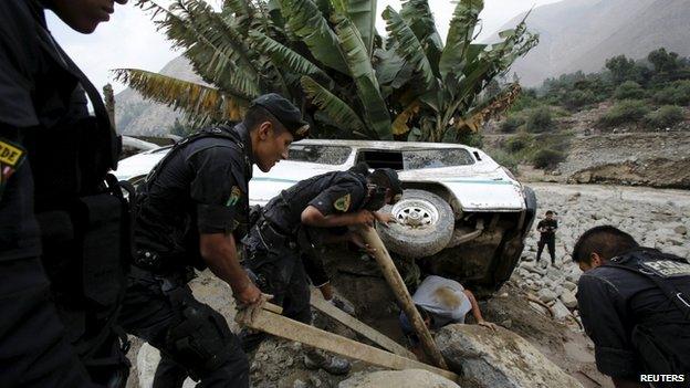 Peruvian police try to remove a car that was stuck in the mud and stones after a landslide in Chosica 24/03/15