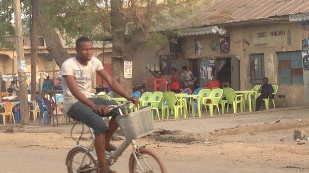 A man riding a bicycle past a bar in Sabon Gari in Kano, Nigeria