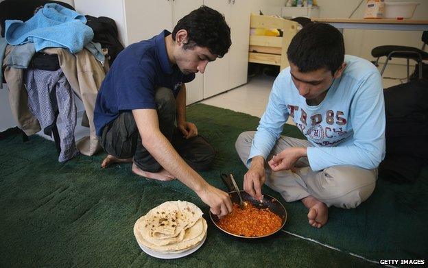 Cousins from Afghanistan eat lunch at a container settlement for refugees in the Allende quarter of Koepenick district on 6 March 2015 in Berlin, Germany