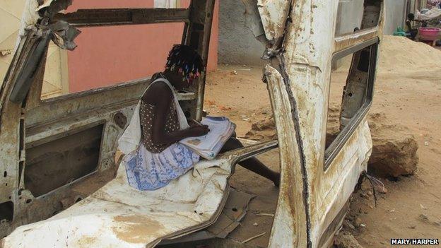 Child doing homework in wreck of car