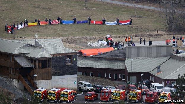 Emergency workers holding up flags representing the nations of the victims of the Germanwings crash at Le Vernet, France