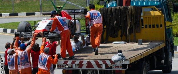 Roberto Merhi's car is hoisted off a truck to the pit area after the Spaniard spun off