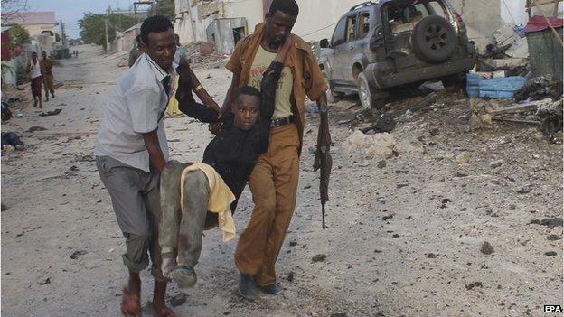 An injured man is evacuated from a scene of a car bomb explosion in front of a hotel in Mogadishu, Somalia, 27 March 2015
