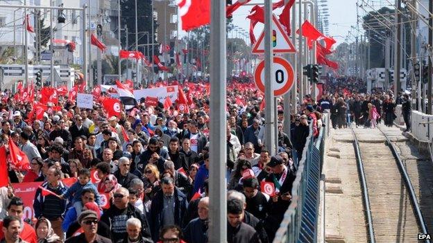 Tunisian people wave the national flag during a march to denounce terrorism, in Tunis, Tunisia, 29 March 2015.