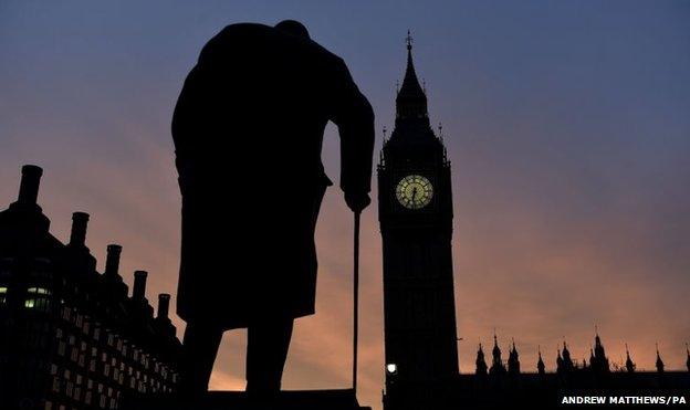 The sun rises behind the Palace of Westminster and the statue of Sir Winston Churchill