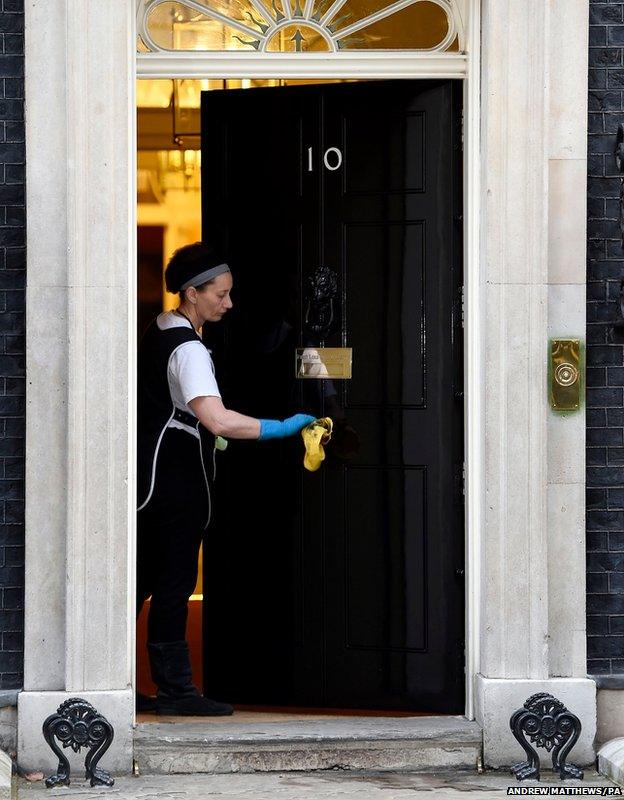 A cleaner polishes the handle of 10 Downing Street