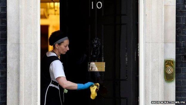 A cleaner polishes the handle of 10 Downing Street