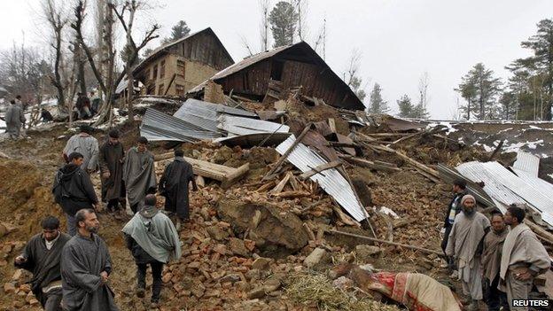 Police stand amidst the rubble after a hillside collapsed onto a house at Laden village, west of Srinagar, March 30, 2015
