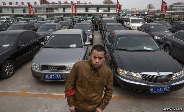 A security guard standing in front of hundreds of government cars due to be auctioned off