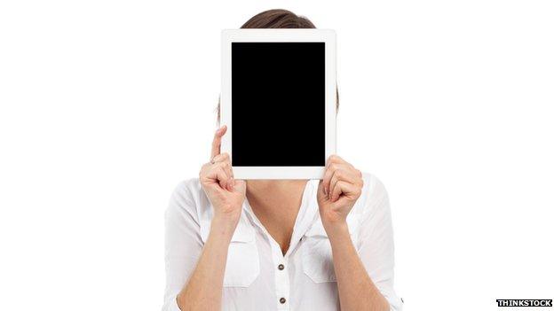 A woman holding a tablet in front of her face