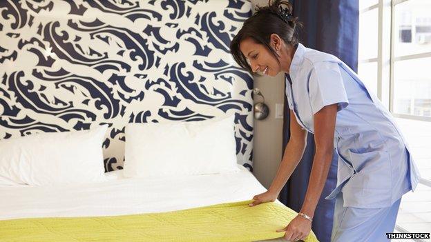 Hotel maid making a bed