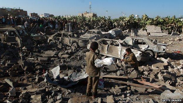 Yemenis stand at the site of a Saudi air strike against Huthi rebels near Sanaa Airport on March 26, 2015