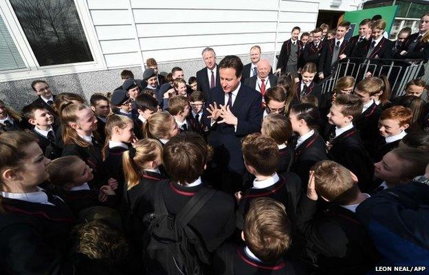 David Cameron (C), talks with pupils during a general election campaign visit to the Kings Leadership Academy in Warrington