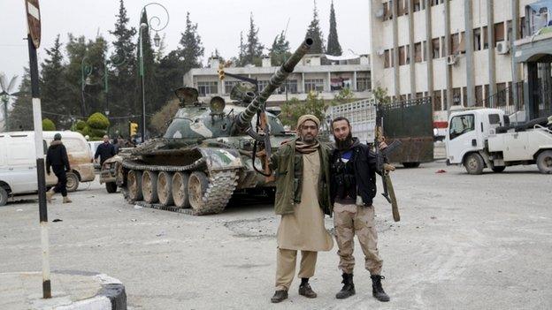 Rebel fighters pose for a picture with their weapons in Idlib city, after they took control of the area