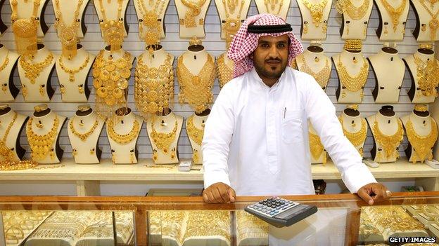 Shop keeper in front of a display of gold