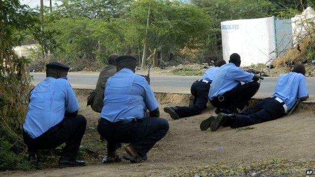 Police officers take cover outside the Garissa University College during an attack by gunmen in Garissa, Kenya, Thursday, April 2, 2015