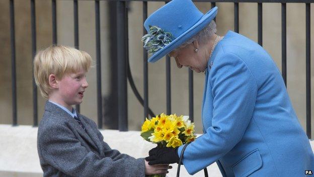 The Queen is presented with flowers by a boy