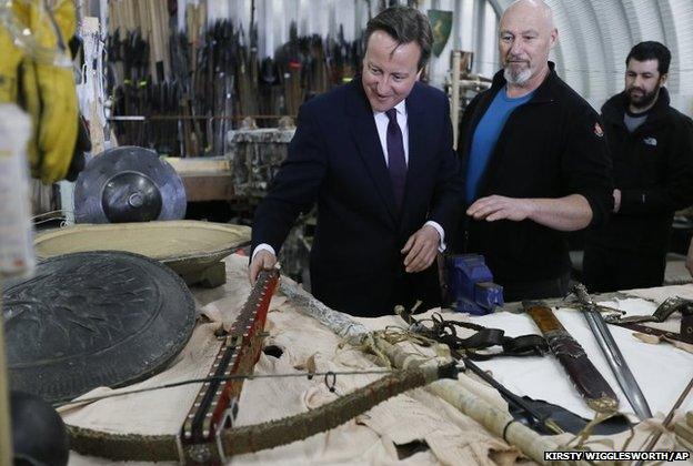 David Cameron, left, looks at a weapon in a workshop, during a visit to the popular TV fantasy drama Game of Thrones television set in Belfast, Northern Ireland,