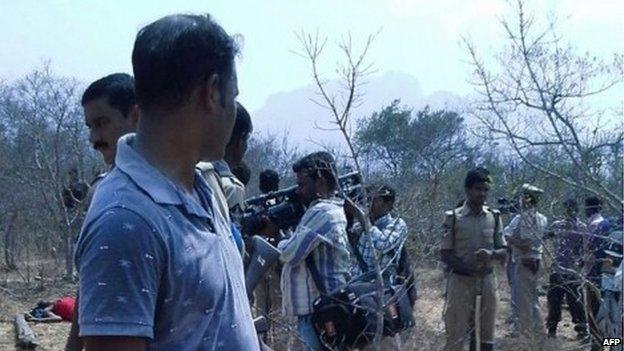 A security guard looks on as members of the media film the bodies of loggers killed by an anti-smuggling task force in a remote forest in the southern state of Andhra Pradesh on April 7, 2015.