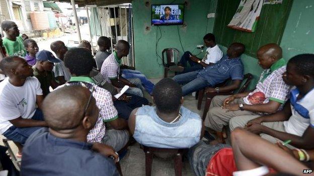 People watch a television in Lagos, on 31 March to follow developments as results of the Nigerian presidential elections are released by the Independent National Electoral Commission