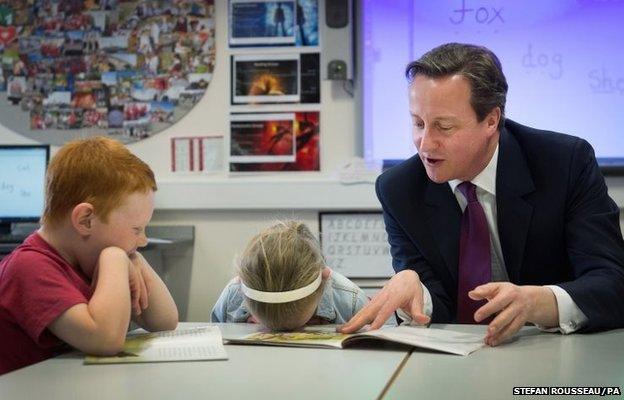 David Cameron helps with a reading lesson at the Sacred Heart Roman Catholic Primary School in Westhoughton near Bolton where he met pupils