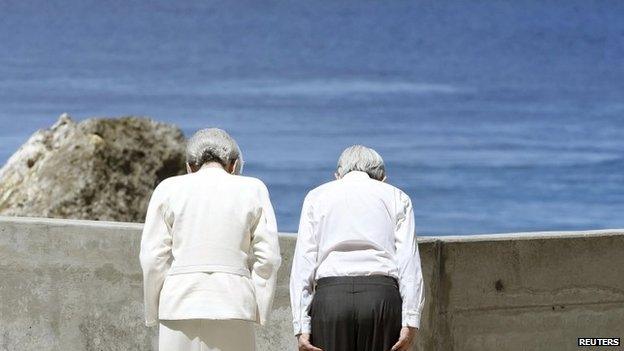 Japan's Emperor Akihito (R) and Empress Michiko bow towards Angaur Island after they offered flowers to the cenotaph for the war dead in the western Pacific area, on Palau's Peleliu Island, on 9 April 2015