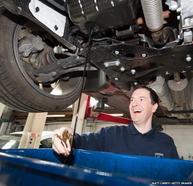 Chancellor George Osborne works under a car that is being serviced at Hawkins Garage near St Austel