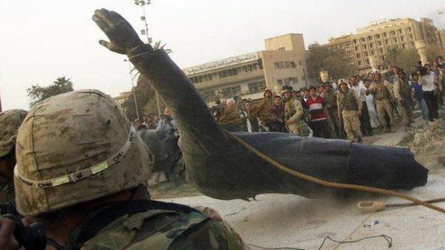 A statue of Saddam Hussein falls as it is pulled down by a US armored vehicle in Baghdad's al-Fardous square 9 April 2003