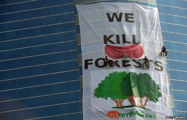 Activists from the environmental group Greenpeace drape the headquarters of India's Essar Group with a giant banner during a protest in Mumbai on 22 January, 2014